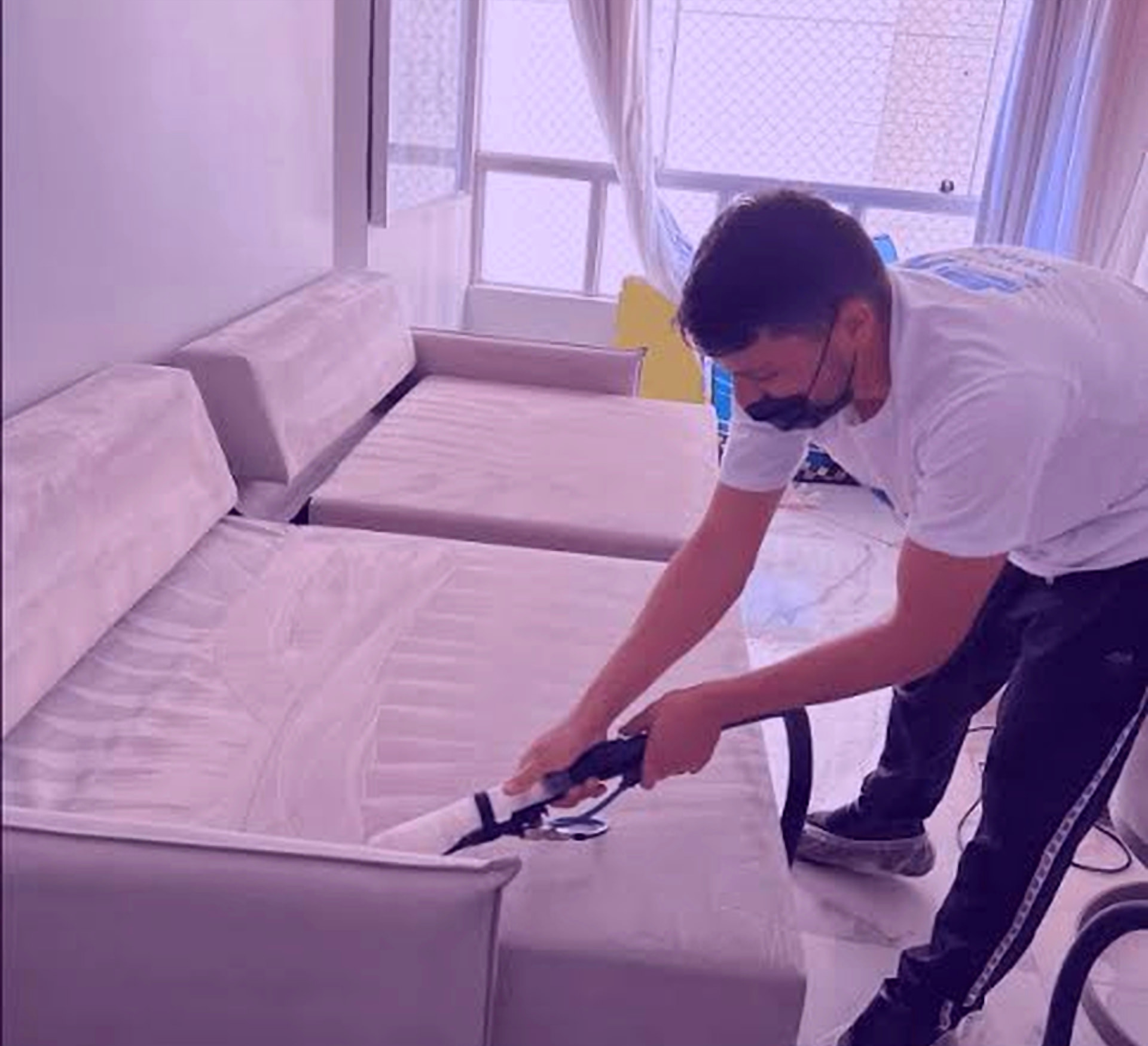 Técnico higienizando sofá de canto claro com extrator em sala residencial de Brasília
